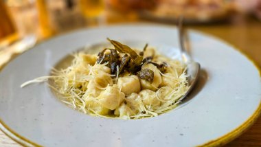 İtalyan yemeği Gnocchi, beyaz tabakta kızarmış salvia, tereyağı ve peynir. Seçici odak