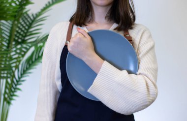 Beyaz arka planda porselen tabağı tutan kadın.