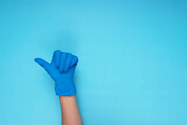 stock image hand in blue medical glove making hand gesture on light blue background