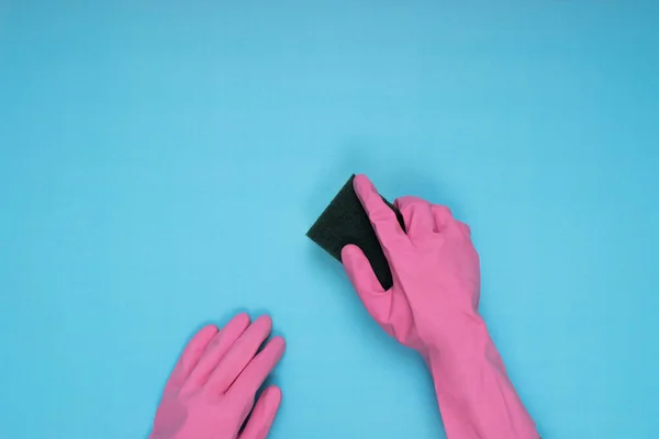 Stock image woman wearing pink cleaning gloves on light blue background holding cleaning sponge