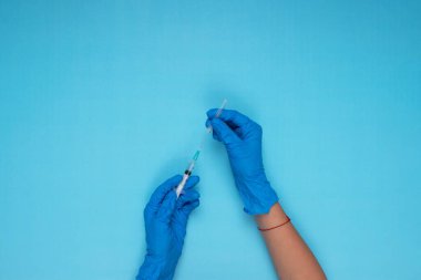 El ele tutuşma iğnesi açık mavi arka planda mavi eldiven