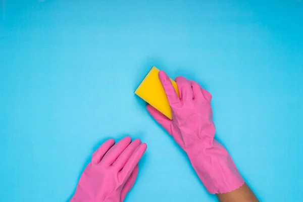 stock image woman wearing pink cleaning gloves on light blue background holding cleaning sponge