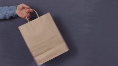 Koyu bir arka planda kağıt torba tutan bir adamın el modeli.