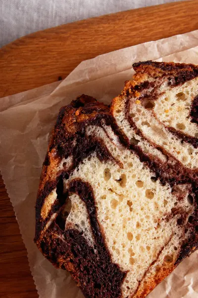 Parşömen kâğıdında çikolata kıvrımlı mermer pasta, kırsal tatlı, ahşap arka plan.