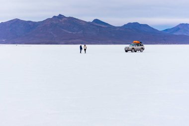 Uyuni 'nin Salt Plats' ında iki turist ve arabaları var.