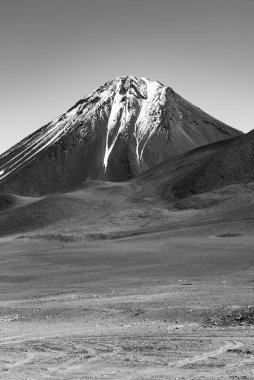 Atacama Çölü 'nde karla kaplı volkanik zirvenin siyah beyaz fotoğrafı