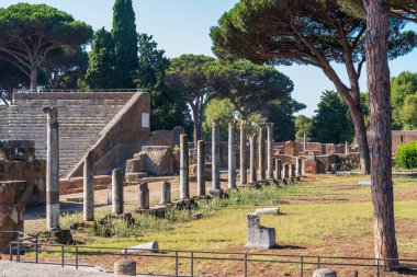 Antik Ostia 'daki arkeoloji parkında harabeler içinde antik Roma amfi tiyatrosu boyunca uzanan cadde
