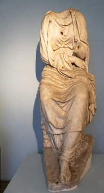 Kafası ve uzuvları olmayan antik mermer heykel kalıntıları tunik giyen bir kadını temsil ediyor.