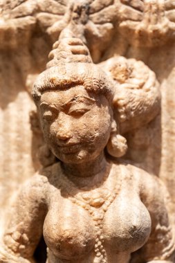 Taş üzerine oyulmuş antik doğu heykeline yakın plan. Göğüsleri açıkta bir kadın portresi.