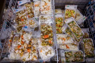 İtalya - 08 Ocak 2023: Karides ve sebzeli deniz ürünleri salatası, midye, mürekkep balığı ve donmuş yumuşakçalar İtalyan süpermarketlerinde satılmak üzere soğutulmuş tezgahlarda paketlenmiştir.