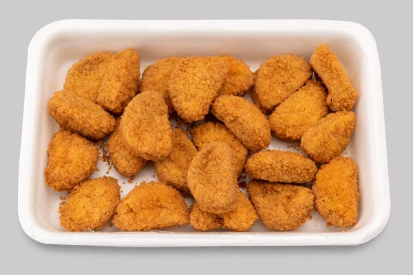 Pre-cooked chicken nuggets in plastic food tray for supermarket sale , isolated on gray with clipping path