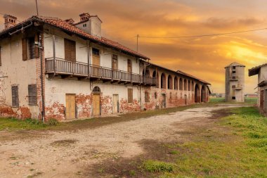 Old abandoned farmhouse with typical rural architecture of the Po Valley in the province of Cuneo, Italy. Rural dwelling with stable and barn under brick arches, grain silo