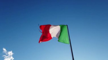 İtalya bayrağı açık mavi gökyüzünde dalgalanıyor, yıpranmış bayrak