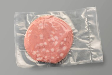 Havasız yemek pişirmek için vakumlu paketteki Mortadella dilimleri gri üzerine izole edilmiş.