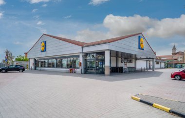 Racconigi, İtalya - 27 Nisan 2023: Bulutlu mavi gökyüzü üzerindeki LIDL indirim mağazasının dışı. Lidl, Almanya 'nın küresel indirimli süpermarket zinciri..