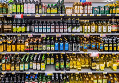 İtalya - 31 Mayıs 2023: Bir İtalyan süpermarketinde satılık raflarda çeşitli marka ve tiplerden oluşan cam şişelerde zeytinyağı
