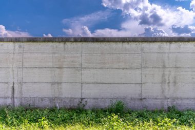 Beton duvar mavi gökyüzü ve bulutlar ve tabanda yeşil çimenler, arka plan desenli, kopyalama alanı