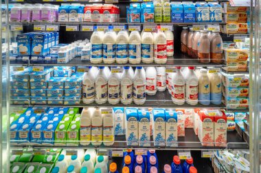 İtalya - 14 Ağustos 2023: İtalyan süpermarketlerinde satılmak üzere soğutulmuş tezgahların üzerindeki taze süt ve çeşitli marka paketleri