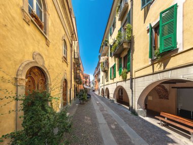 Cuneo, Piedmont, İtalya - 16 Ağustos 2022: Contrada Mondovi, tarihi merkezdeki eski renkli binaların altındaki antik parke taşı caddesi