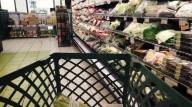 İtalya - Ağustos 02, 2023: İtalyan süpermarketi koridorunda hazır temiz salata ve sebze paketleriyle soğutulmuş raflar arasında alışveriş arabaları taşınıyor. 