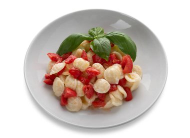 Taze domates, zeytinyağı ve beyaz tabaktaki fesleğenli yapraklarla tatlandırılmış makarna. Kesme yolu da dahil. Tipik İtalyan Apulian tarifi.