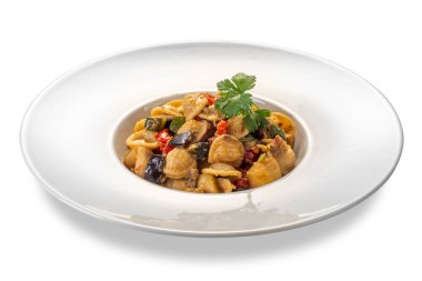 Patlıcan, kabak, domates sosu ve beyaz tabakta izole edilmiş maydanoz yapraklarıyla pişirilmiş makarna.