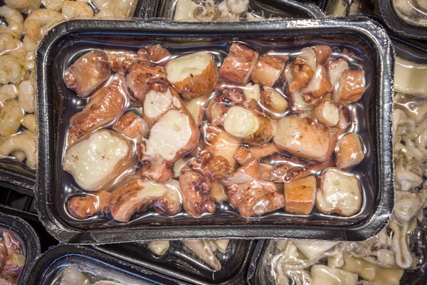 Octopus tentacles in pieces in vacuum-sealed trays for sous vide cooking for sale in supermarket refrigerated counters