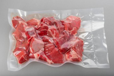 Çiğ sığır eti yahnisi, bir parça çiğ et, vakum paketlenmiş gri arka planda pişirmek için sous vide