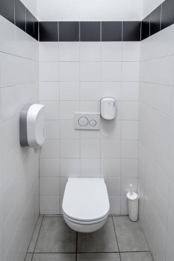 Kağıt tutacağı ve alışveriş merkezinde tuvalet fırçası olan beyaz tuvaletli fayanslı tuvaletler. 