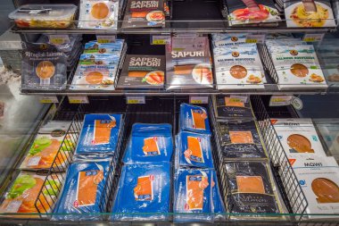 İtalya - 20 Kasım 2023: Çeşitli türde paket ve markalardan tütsülenmiş somon balığı İtalyan süpermarketinin soğutulmuş tezgahında satılmaktadır.