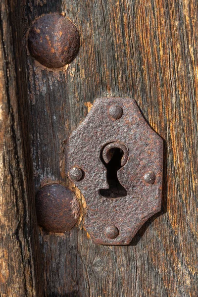 Antique rusty metallic keyhole on old wooden door, close up