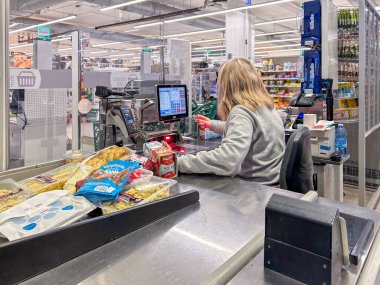 İtalya - 12 Ocak 2024: Süpermarket kasiyerinin İtalyan süpermarketinden satın aldığı ürün okuyucusunu elden geçirmesi