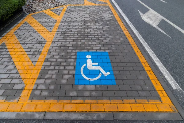 Handicapped parking marked by yellow lines and the blue disability symbol in a parking lot.