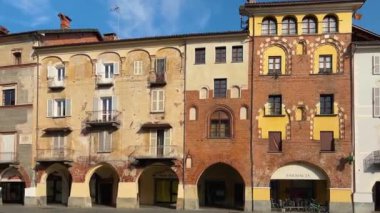 Savigliano, Cuneo, Piedmont, İtalya - 21 Mart 2024: Tarihi ortaçağ kökenli Piazza Santarosa binaları ve atari salonu ve St. Andrea 'nın zafer kemeri manzarası