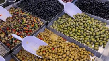 Çeşitli türde zeytinler ve çeşitli pişirme süreçleri bir Sicilya pazarında satılık tezgahlarda sergileniyor. İleri git ve üst görüntüde geri git