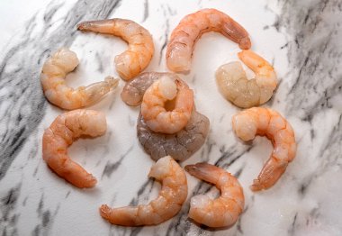 Raw shelled shrimp on white marble streaked with black clipart