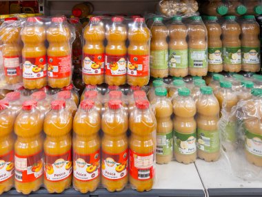 İtalya - 01 Haziran 2024: Şeftali ve armut meyve suyu ve posa indirimli süpermarketlerde satılmak üzere raflarda plastik şişelerde satılıyor