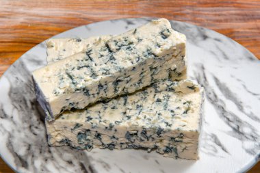 Gorgonzola peyniri, ahşap masada mermer tabakta tipik İtalyan mavi peynirinden dilimler.