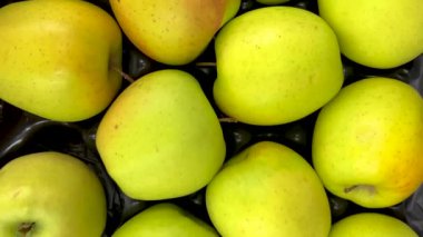 Manavın tezgahında, arkaplan dokusunda altın aromalı elmalar görünüyor.