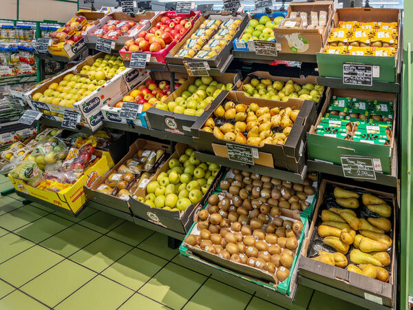 Италия - 2 июля 2024 года: Яблоки, груши и киви в коробках, выставленных на полку в зеленом отделе для продажи в итальянском супермаркете