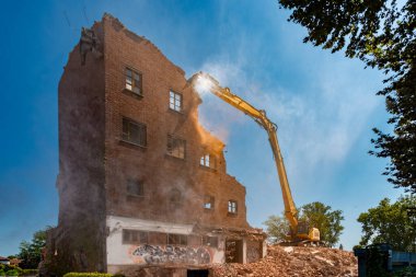 Eski endüstriyel tuğla yapısının kazıcıyla birlikte hidrolik beton parçalayıcı ile yıkılması, Corso Savona, Asti, İtalya 'daki eski değirmenin yıkılması