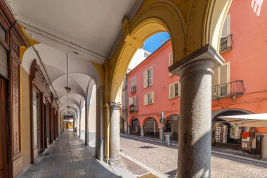 Asti, İtalya - 20 Ağustos 2024: Via Pietro Gobetti 'deki tarihi merkezde taş sütunlu antik binalar, kaldırım taşı kaldırımlı bir cadde.