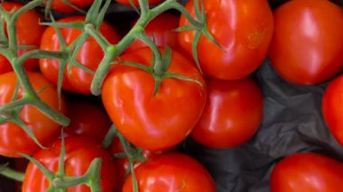 Meyve dükkanında sergilenen küme domatesler, kırmızı domateslerin üst görüntüsünü takip ediyor.