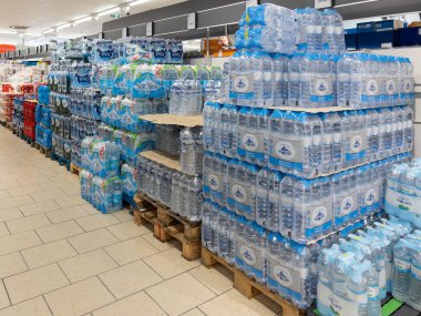 İtalya - 12 Ekim 2024: İtalyan süpermarket koridorlarında sergilenen paletlerin üzerine istiflenmiş çeşitli markalardan oluşan plastik şişelerde su