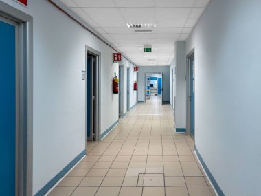 İtalyan hastanesinin koridorunda duvarlarında kırmızı yangın söndürücüler asılı.