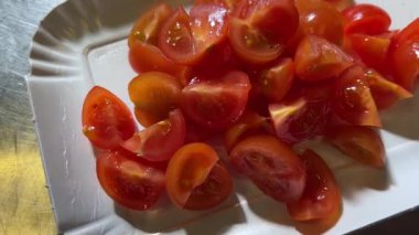 Beyaz karton bir tepside kesilmiş kiraz domatesleri, yukarıdan zoom yaparak çekim yapıyorlar.