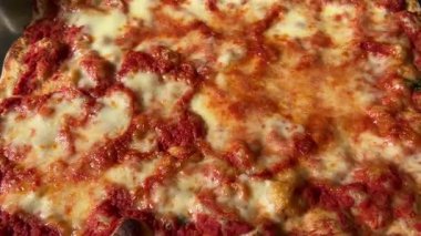 Domates sosu ve erimiş mozzarella peyniriyle yakın çerçeveli büyük kare pizzanın izini sürüyorum.