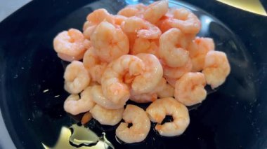 Yuvarlak resimli, siyah tabakta soyulmuş karides.