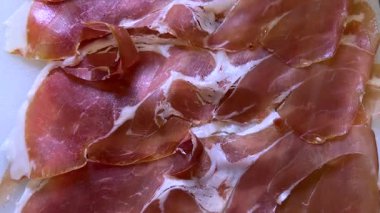 Beyaz kesim tahtasında parma jambonu dilimleri, üst görüntüde iz sürme. 