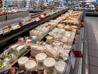 İtalya - 11 Haziran 2025: İtalyan süpermarket koridorunda çeşitli paketlenmiş peynirlerle birlikte büyük soğutmalı tezgah